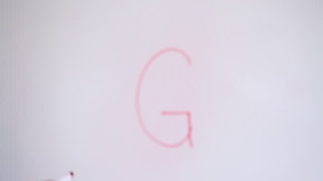 Hand Writing Capital Letter G On White Board With Red Marker