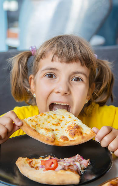 istock Cute Girl Eating Pizza At Table In Restaurant 1414480555
