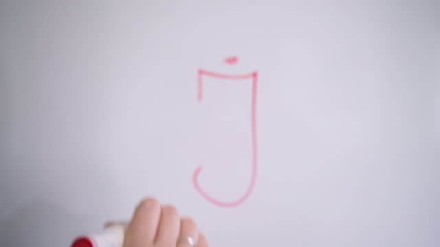 Hand Writing Capital Letter J On White Board With Red Marker