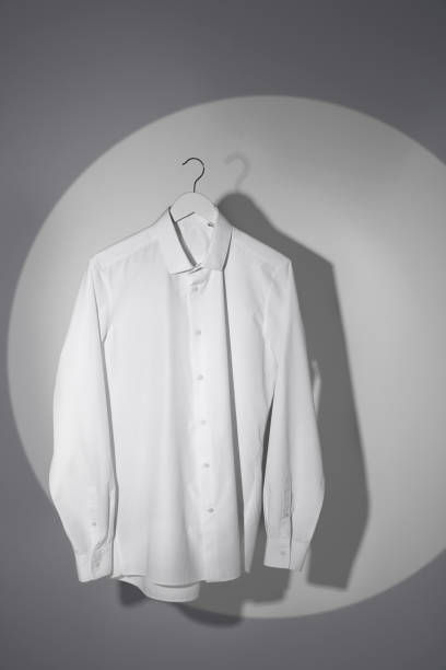 istock Stylish men's shirt hanging on light wall 1414484151