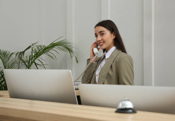 Beautiful receptionist talking on phone at counter in hotel