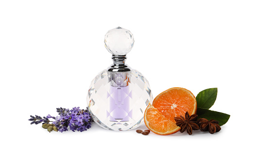 Bottle of perfume, tangerine, flowers and spices on white background