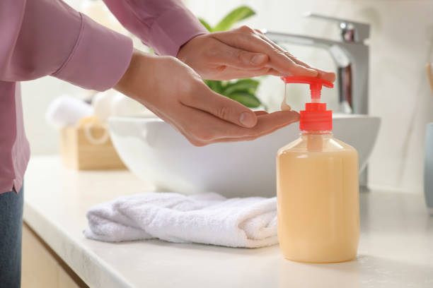 istock Woman using liquid soap dispenser in bathroom, closeup 1414484939