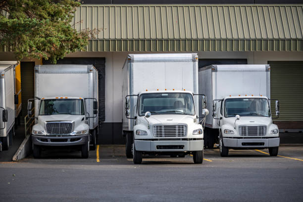 istock Middle duty rigs semi trucks with box trailers standing in warehouse dock with gates loading cargo for delivery 1414485683