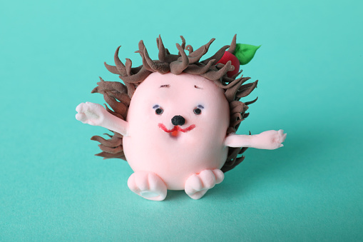 Small hedgehog made from play dough on turquoise background