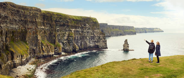 dos amigas mirando los acantilados de la costa - cliffs of moher republic of ireland panoramic cliff fotografías e imágenes de stock