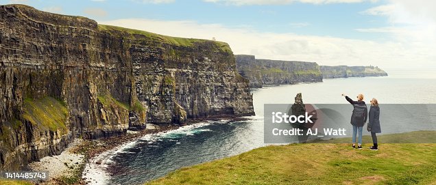 istock Two woman friends looking at coastline cliffs 1414485743