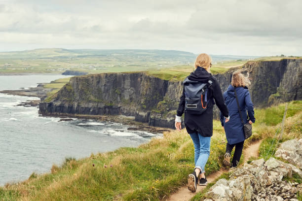 deux amies marchant sur le sentier sur la falaise - republic of ireland cliffs of moher landscape cliff photos et images de collection