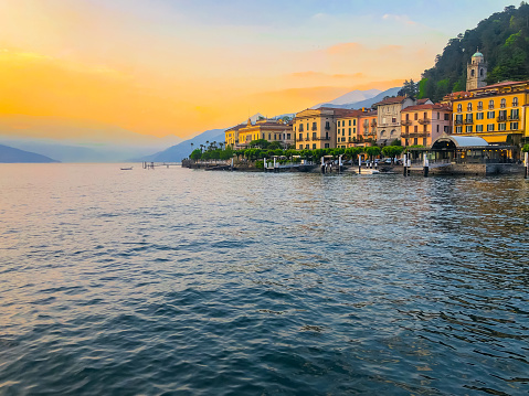 View of houses in old town by famous lake and mountains against sky during sunset