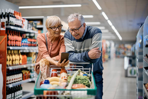 istock Happy senior couple using app on mobile phone while shopping in supermarket. 1414488121