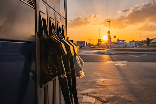 Close-up of petrol pump filling nozzles on gas station during sunset