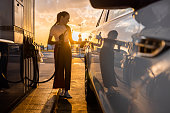Young woman refueling her car at gas station