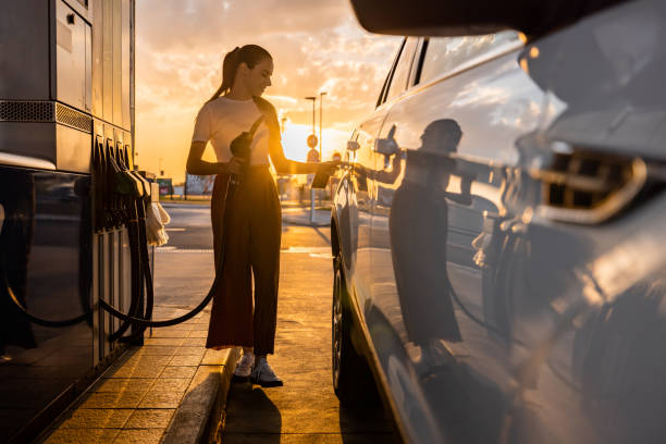 Young woman refueling her car at gas station stock photo