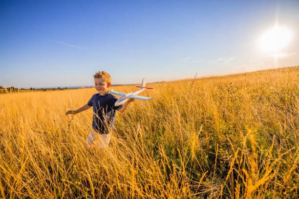 istock Smiling boy playing with toy amidst grassy field in meadow 1414489380