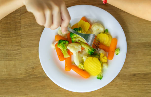 The child eats vegetables on a chair. Selective focus. Kid.