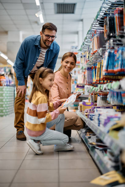 Happy family buying school supplies in supermarket. Happy parents and their daughter shopping school supplies in supermarket. shopping photos stock pictures, royalty-free photos & images