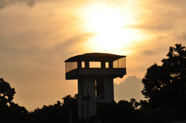 Sun glowing behind watch tower at National Botanical Garden, Dhaka, Bangladesh in afternoon.