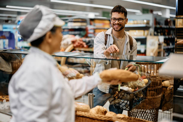 istock Young happy man buying bread in supermarket bakery. 1414489733