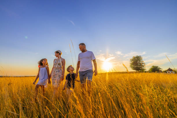 istock Parents talking to children while walking together on grassy field 1414490005