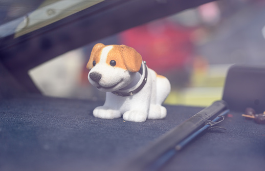 A nodding toy dog on the dashboard of a car on a window background