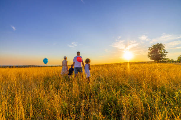 istock Parents walking with children on grassy field against sky 1414490325
