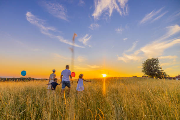 istock Parents walking with children holding balloons while exploring in meadow 1414490401