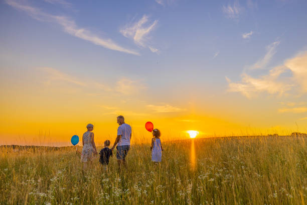 istock Happy family talking while walking together in meadow against sky 1414491058