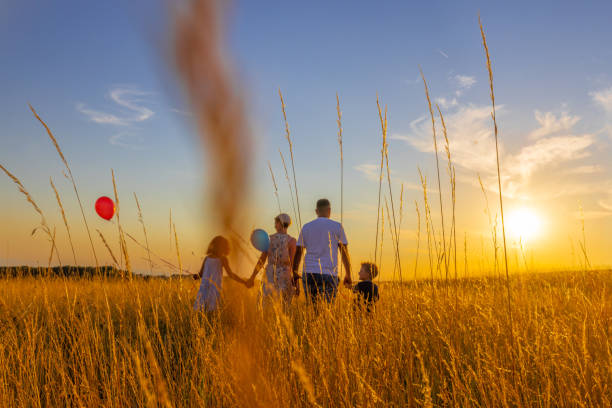 istock Parents talking to children while walking in meadow against sky 1414491303