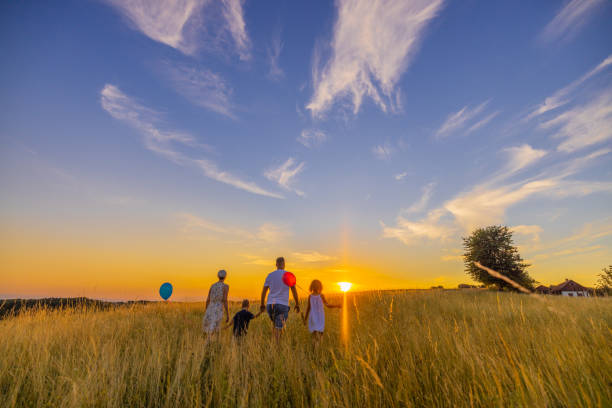 istock Children holding balloons while walking with parents exploring in meadow 1414491422