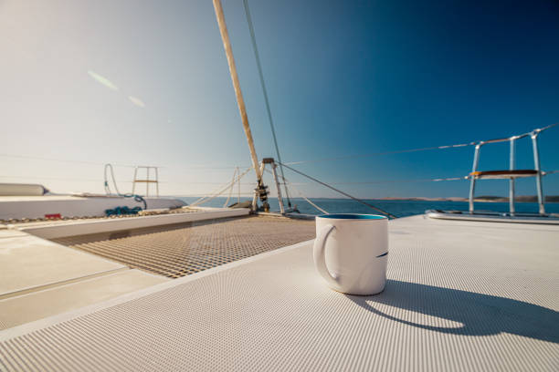 Empty coffee cup on white boat deck against clear blue sky during sunny day