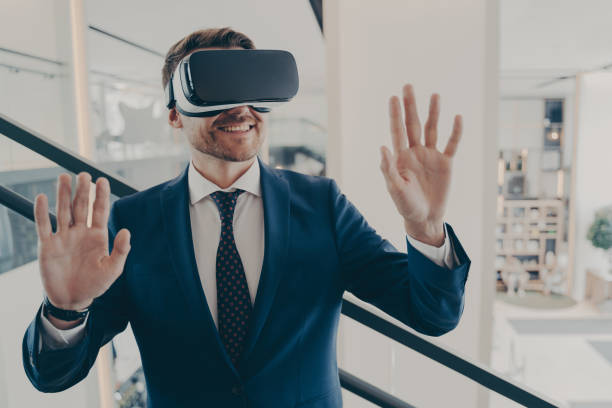 istock Young excited man office worker using virtual reality simulator at work, moving hands in air 1414492506