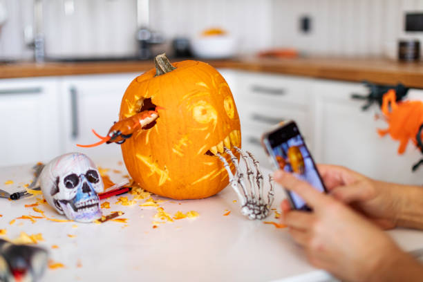 istock Man making photo for mobile of pumpkin for halloween 1414493146