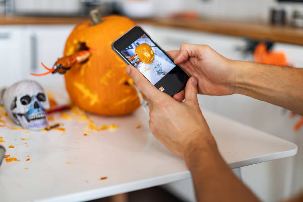 istock Man making photo for mobile of pumpkin for halloween 1414493149
