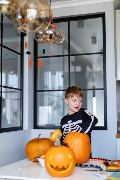 istock Boy celebrating halloween at home and preparing pumpkins 1414493361