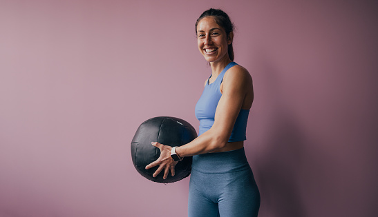 Portrait of a sportswoman holding a medicine ball in the gym.