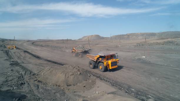 istock Wide dirt road with huge mining trucks moving towards each other on it 1414502482