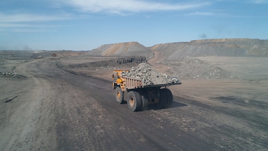 Wide dirt road with huge mining trucks moving towards each other on it.