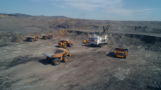 Loading queue from giant dump trucks to mining excavator. Open pit coal mining.