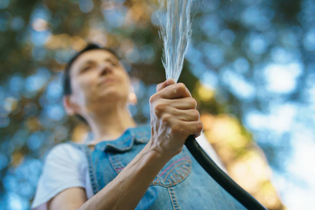 A close-up photo of a woman's hand while watering a garden.