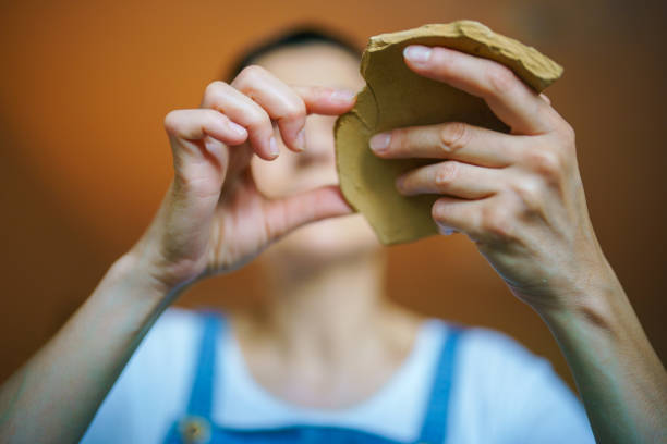 Close up to human hand holding a ceramic piece