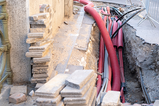 Network cables in red corrugated pipe are buried underground on the street. underground electric cable infrastructure installation. Construction site with A lot of communication Cables
