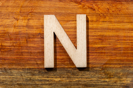 Wooden letters N on wooden background, top view