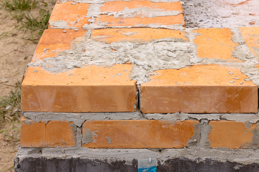 initial rows of brickwork. the initial stage of building a house. masonry of orange ceramic bricks.