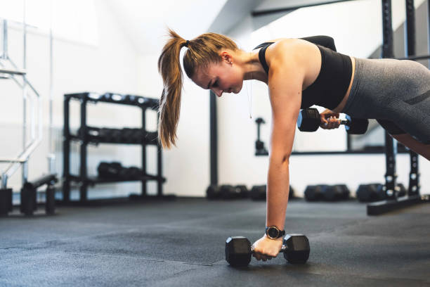istock Waist up woman lifting dumbbells while holding a plank 1414521006