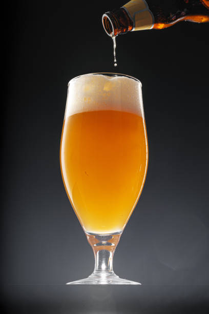 istock Beer pouring into glass on black background 1414528628