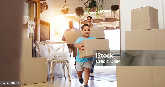 istock Happy family moving into new home and cheerful or excited child son and parents carrying boxes into their house. First time home owners looking satisfied with real estate property while settling in 1414528732