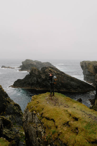 istock Photographer stands on pinnacle above sea 1414531579