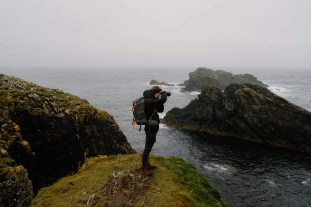 istock Photographer stands on pinnacle above sea 1414531580