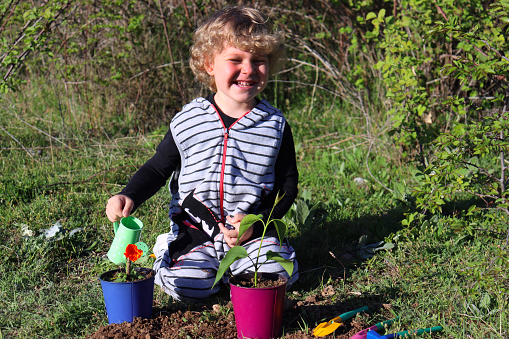 Blond boy watering flowers