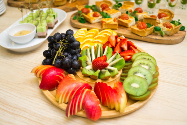 An appetizer of sliced fresh ripe fruit on a wooden round tray stock photo